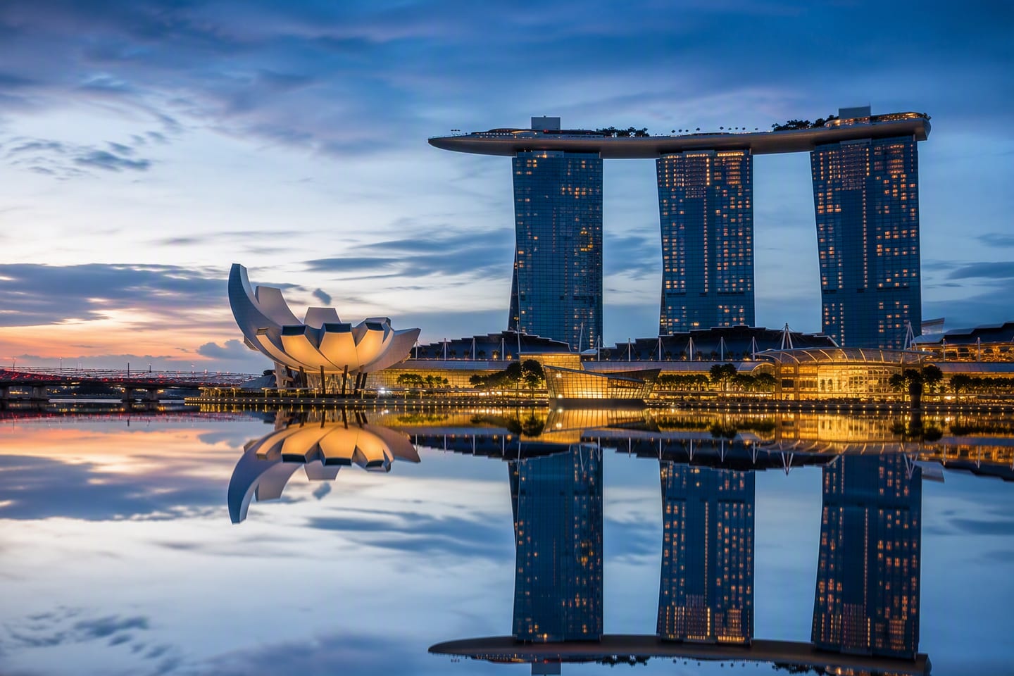 Singapore’s Marina Bay skyline glows at blue hour, with Marina Bay Sands and the ArtScience Museum reflected crisply in the calm waterfront.