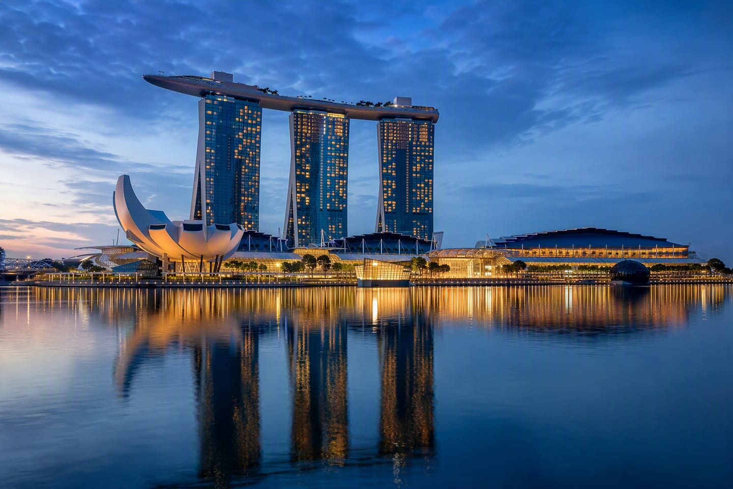 Singapore’s Marina Bay skyline glows at blue hour, with Marina Bay Sands and the ArtScience Museum reflected across the calm waterfront.